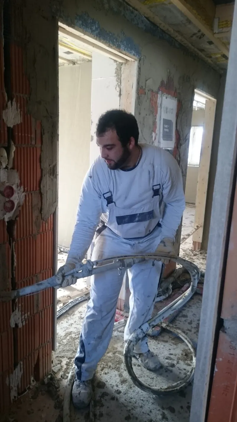 Mitarbeiter der Topal GmbH führt den Estrichschlauch durch eine Türöffnung im Altbau